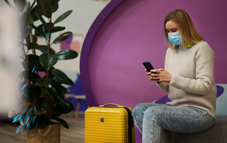 Woman in medical mask with smartphone at the airport.