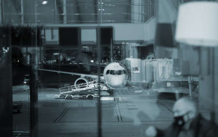 Passenger plane docked to terminal gate at night airport.の写真素材