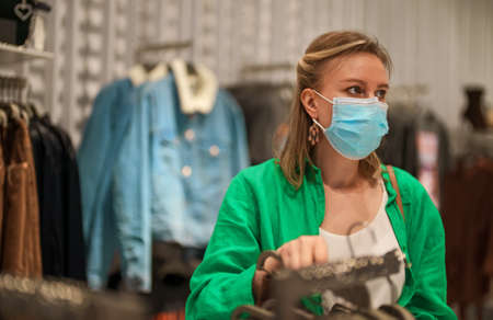 Woman in medical mask choosing clothes in the store.の写真素材