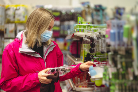 Woman in medical mask is choosing products for home.の写真素材