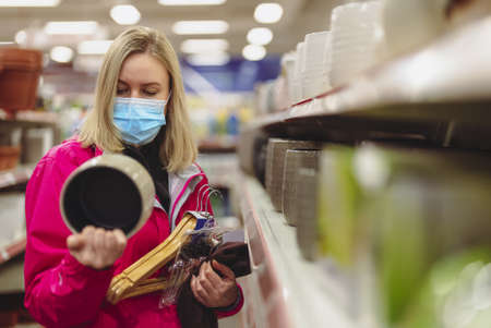 Woman in medical mask is choosing flower pot.の写真素材