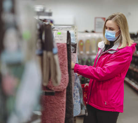 Woman in medical mask is choosing bath mat.の写真素材
