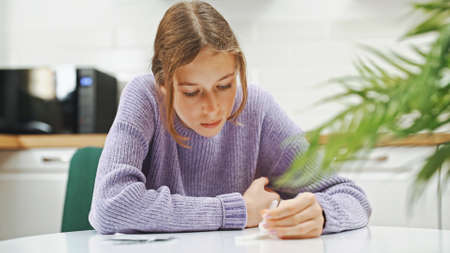 Schoolgirl doing express COVID-19 antigen test at home.の写真素材