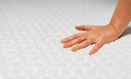 Woman hand testing orthopedic memory foam mattress.の写真素材