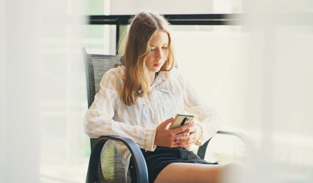 Tween girl with smartphone sitting on balcony.