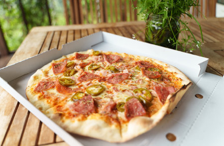Crispy hot pizza with ham, pepperoni and jalapeno.の写真素材