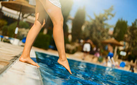 Woman checking water in the swimming pool.の写真素材