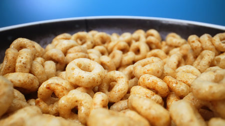 Bowl with cereal circles on blue background.