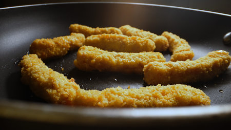 Chicken nuggets frying in a pan.