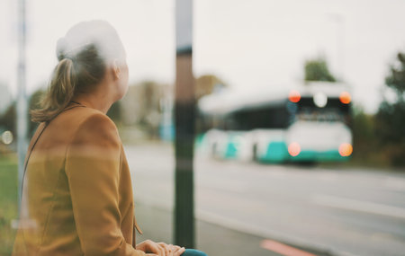 Woman is waiting for bus at bus stop.