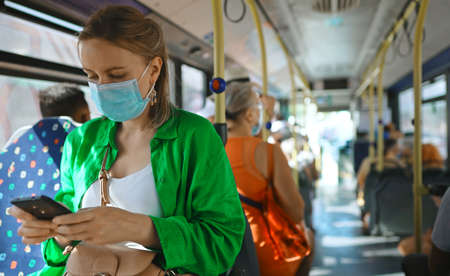 Woman in medical mask with mobile phone in the bus.の写真素材