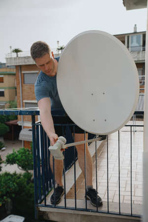 Male worker installing dish for TV.の写真素材