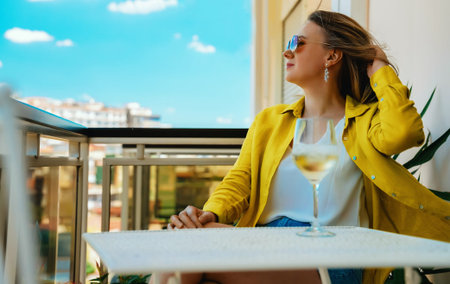 Woman with white wine enjoys her vacations on the balcony.