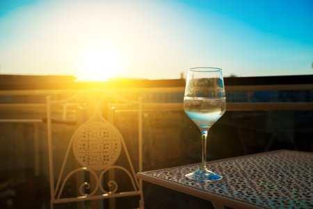 Glass of white wine on the balcony at sunset.