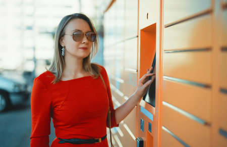Woman picks up mail from automated self-service post terminal machine.