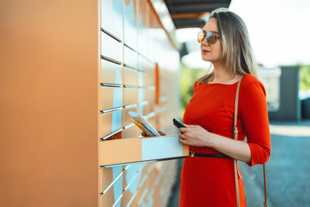 Woman picks up mail from automated self-service post terminal machine.