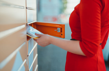 Woman picks up mail from automated self-service post terminal machine.