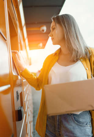 Woman sending mail via automated self-service post terminal machine.の写真素材