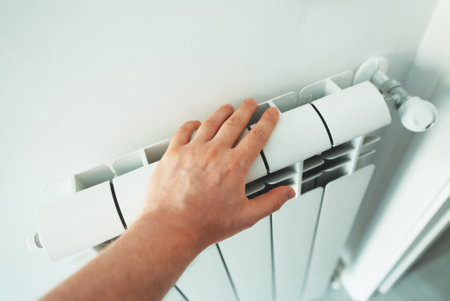Man's hand checking temperature of heating radiator.の写真素材