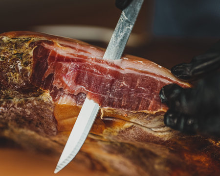 Chef cutting dry-cured spanish ham Jamon.