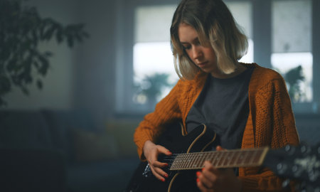 Teenage girl learning to play semi-acoustic guitar.の写真素材