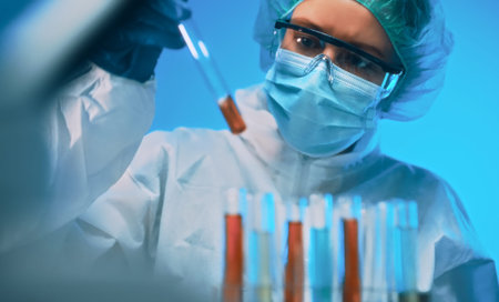 Woman in goggles and mask working with test tubes in laboratory.