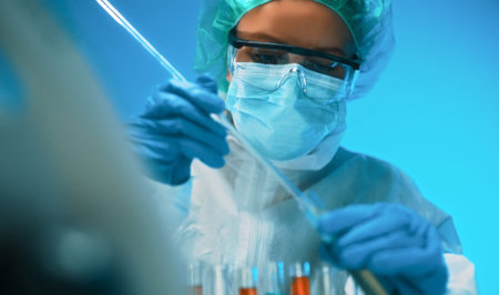 Woman in goggles and mask working with test tubes in laboratory.