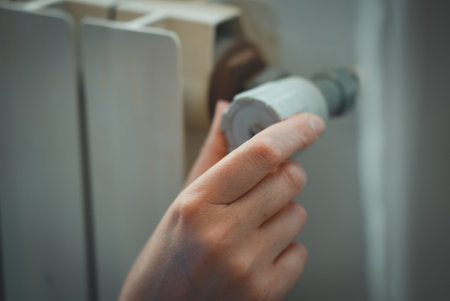 Female hand adjusting thermostat to turn on the radiator heater at home.の写真素材