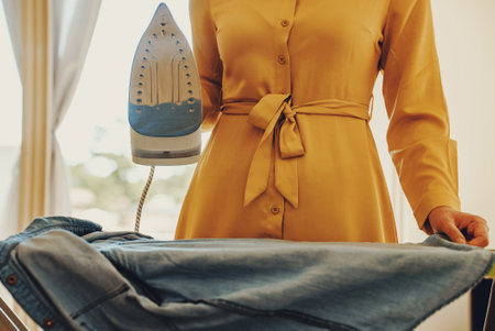 Woman in a yellow dress is ironing clothes.の写真素材