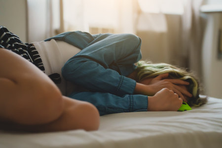 Upset teen girl on bed with phone.の写真素材