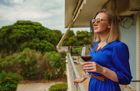 Woman enjoys red wine on her balcony.の写真素材