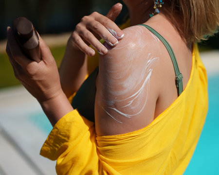Woman applying sunblock cream on her shoulder.の写真素材