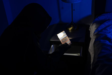 Female thief steals money from the bedside table.の写真素材