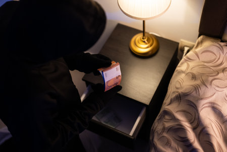 Female thief steals money from the bedside table.の写真素材