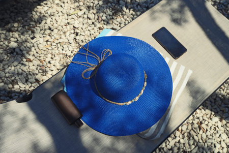 Blue hat, sunscreen and towel on a sun lounger.