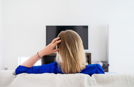 Woman is waiting for a movie to load on the TV. Slow Internet connection.
