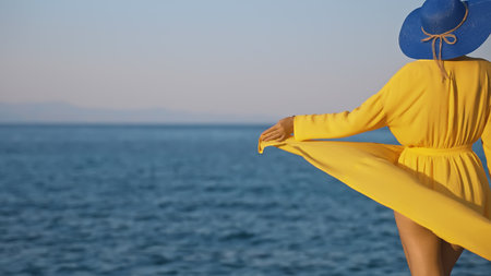 Woman in yellow dress against the ocean.の写真素材