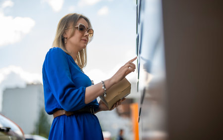 Woman sending mail via automated self-service post terminal machine.の写真素材