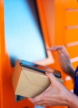 Woman sending mail via automated self-service post terminal machine.の写真素材