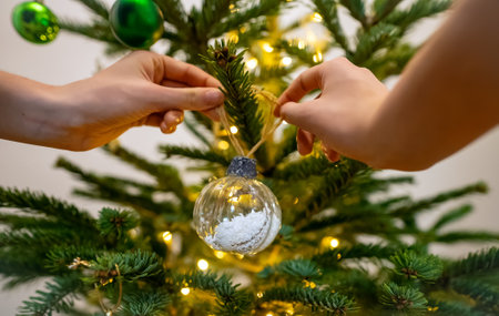 Woman hangs a ball on a New Year tree.の写真素材