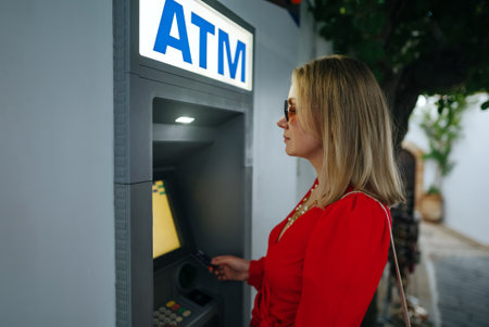 Woman using ATM on the street.の写真素材