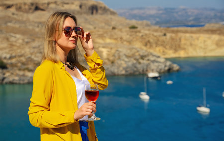 Woman in sunglasses with red wine on the balcony.の写真素材