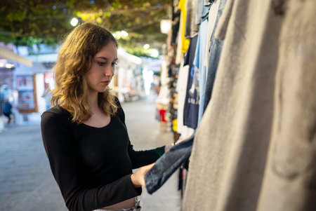 A girl chooses clothes for herself at a street market.の写真素材