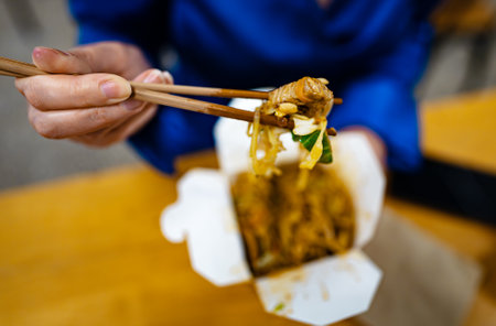 Woman eating noodles with vegetables and meat from Chinese.の写真素材