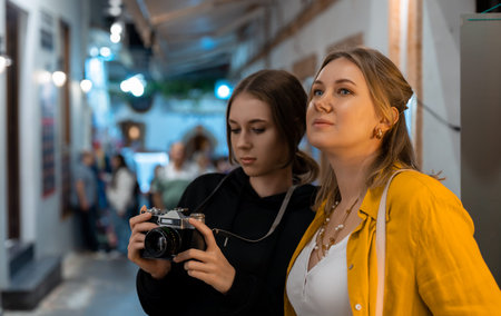 Two girls with retro camera exploring old city.
