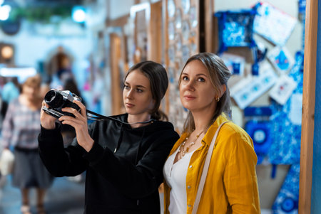 Two girls with retro camera exploring old city.