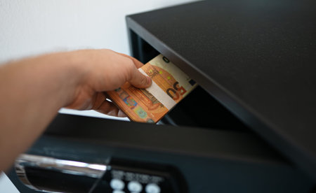 Man puts or takes euro banknotes from a safe.