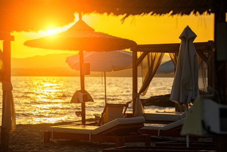 Beach cabana beds and sun loungers on the seashore at sunset.の写真素材