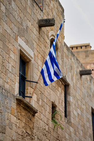 The Greek flag hangs on the wall of the building.