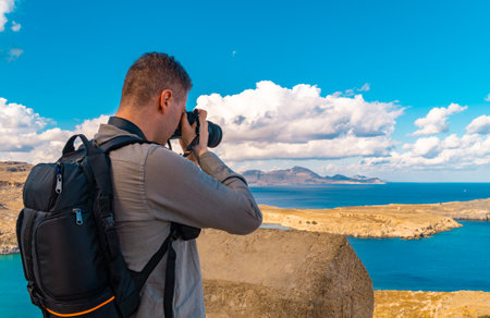 Man takes a photograph of Lindos Bay.の写真素材